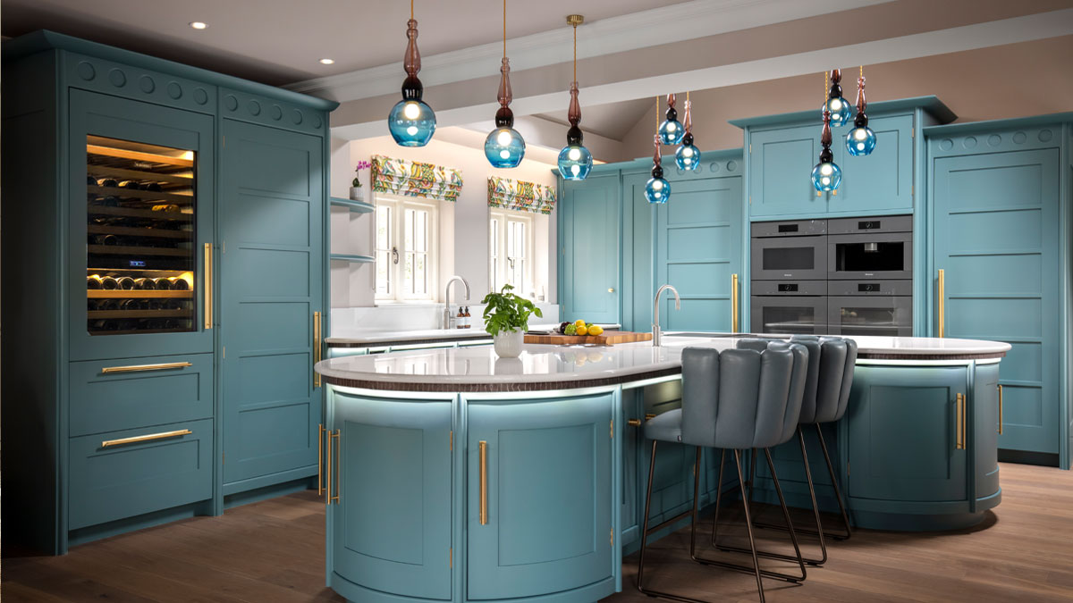 Blue hand-blown glass round pendant lights with purple glass stem hanging above a blue modern shaker style kitchen designed by chiselwood.