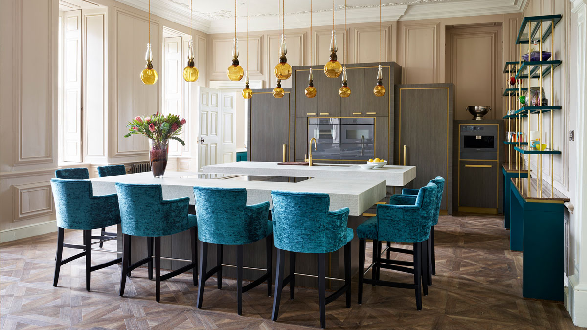 Hand-blown yellow and olive green glass pendant lights hanging above a contemporary kitchen island in a large luxury kitchen designed by Chiselwood.