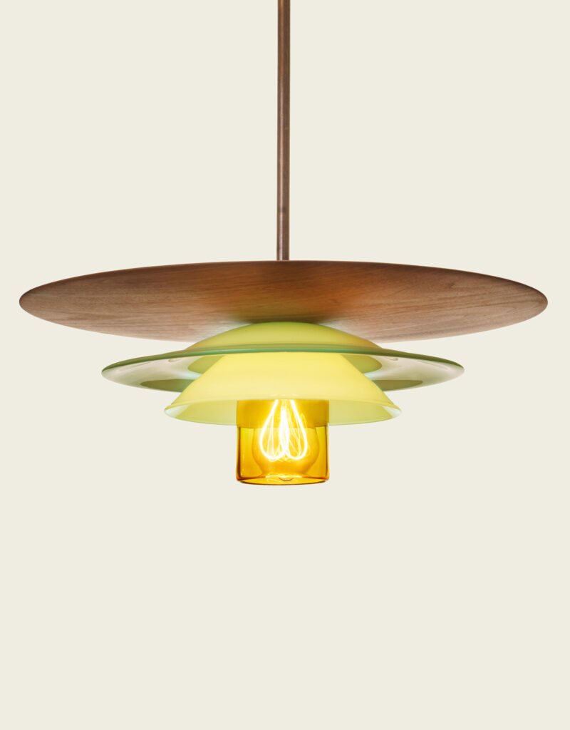 Large statement pendant light made from a hand-made walnut wooden disc and layered hand-blown glass in yellow, and pastel green.
