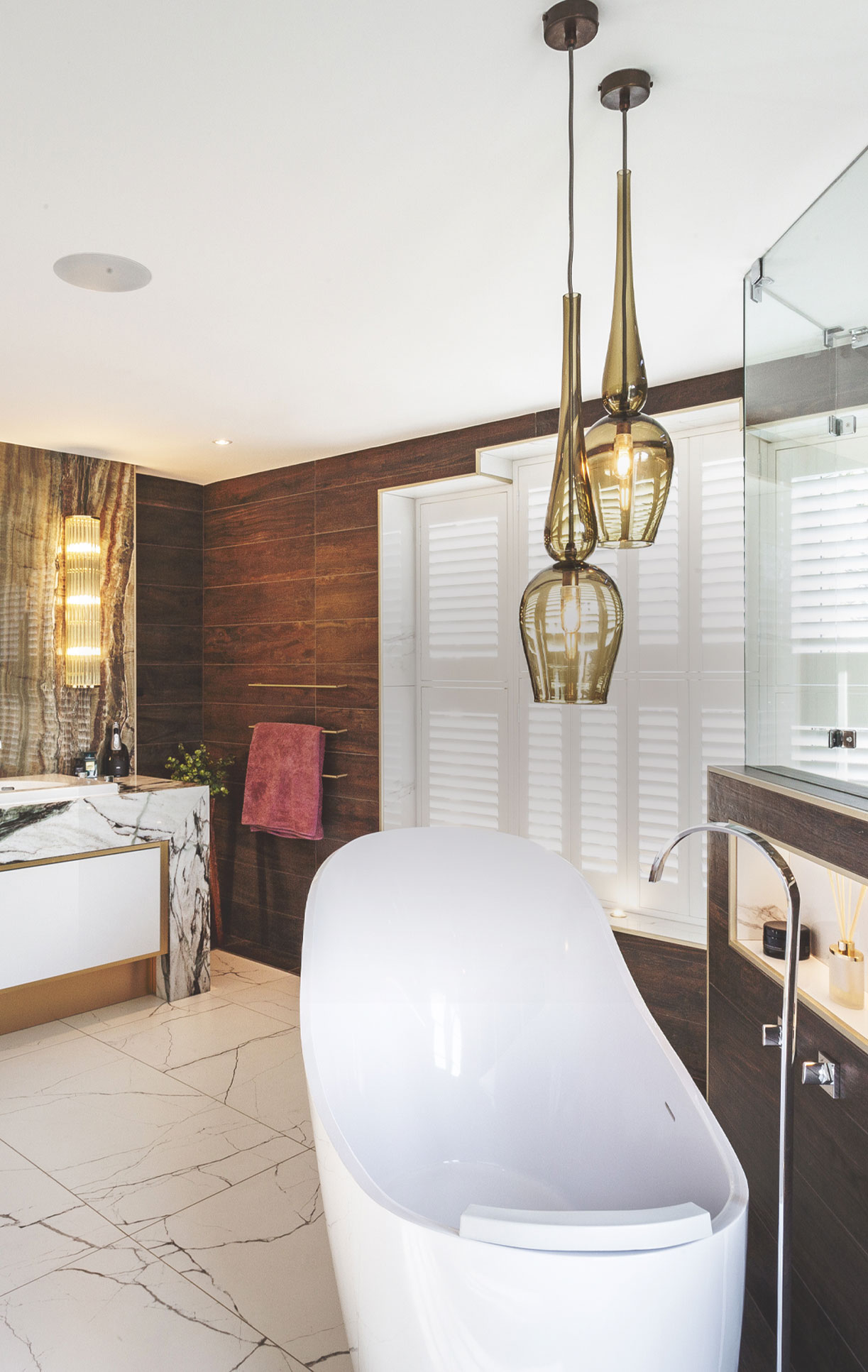 Green glass sculptural bathroom pendant lights hanging over a free standing bath in a contemporary bathroom.